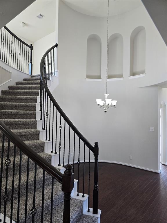 a view of staircase with railing and a chandelier