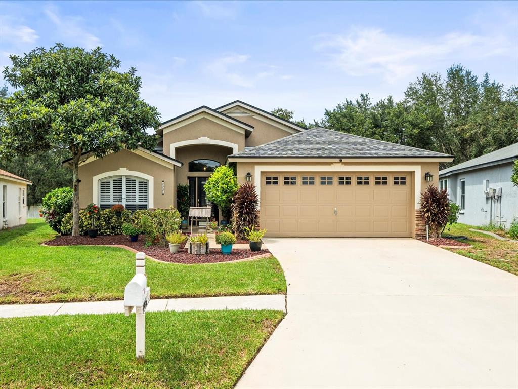 a front view of a house with a garden and trees