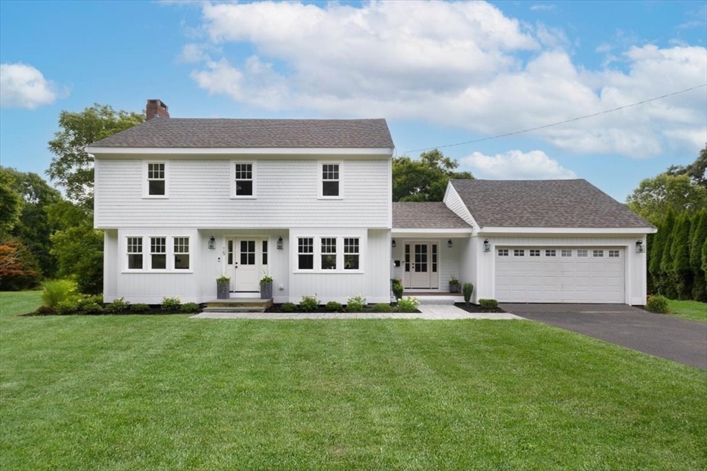 a big white house with a big yard and potted plants in front of it