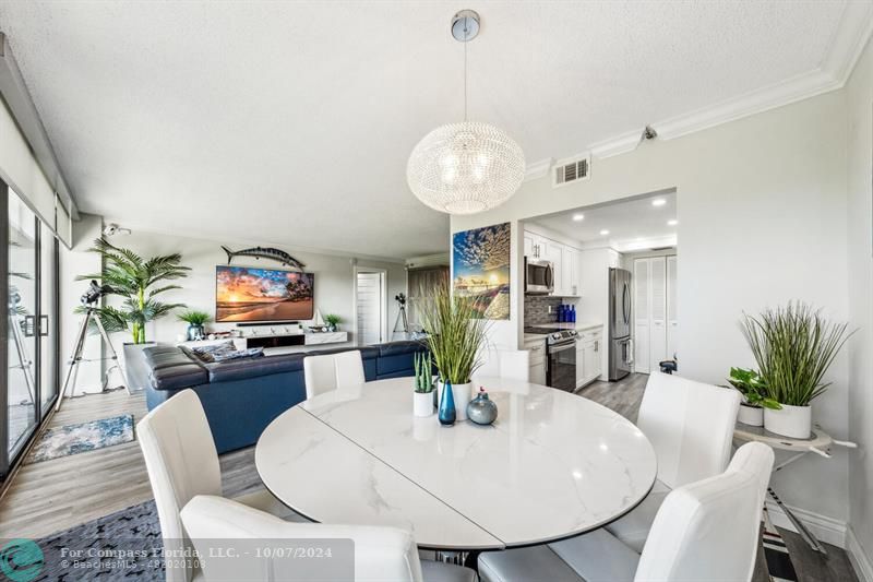 a view of a dining room with furniture a kitchen and chandelier