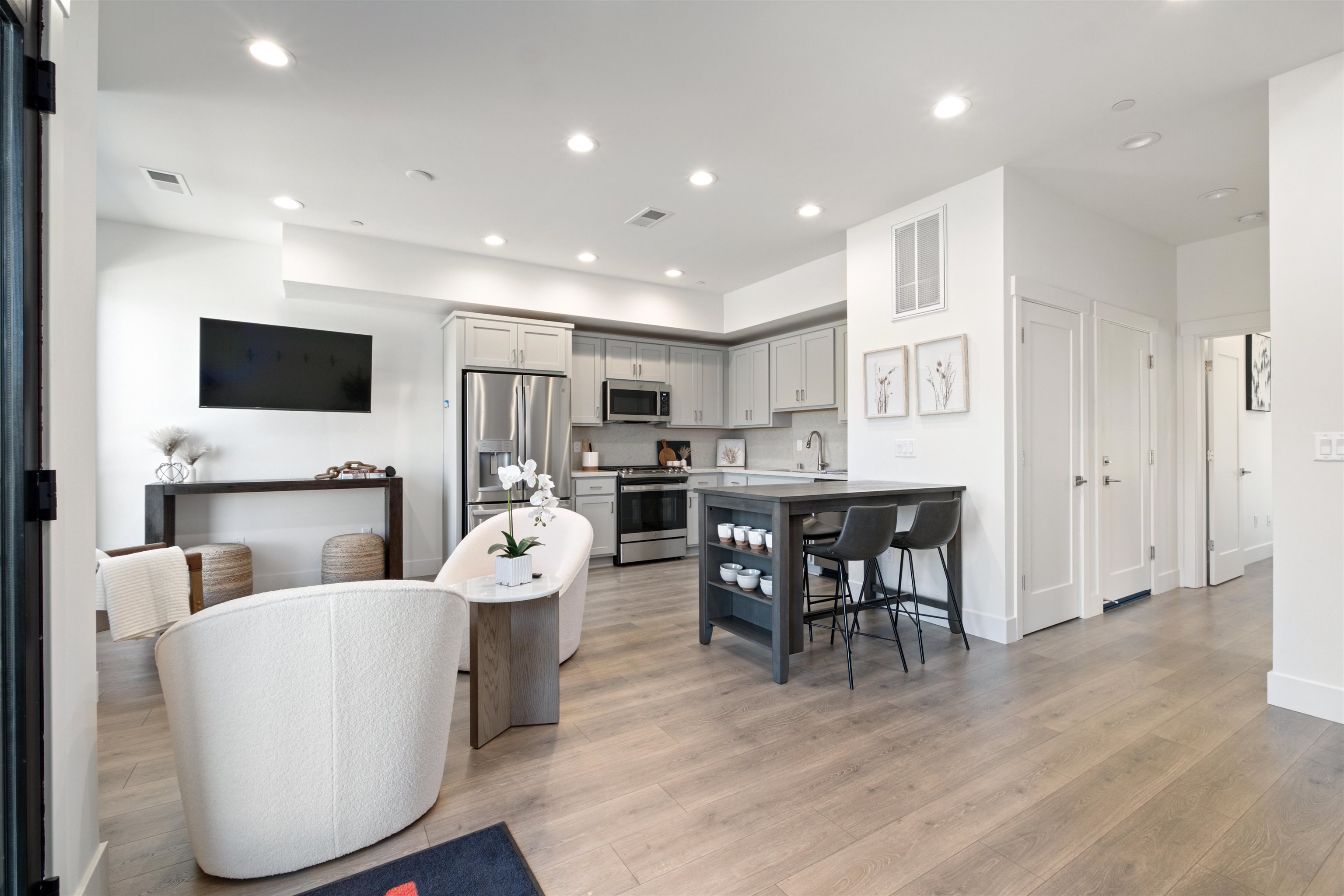 a living room with stainless steel appliances furniture a fireplace a flat screen tv and a kitchen view