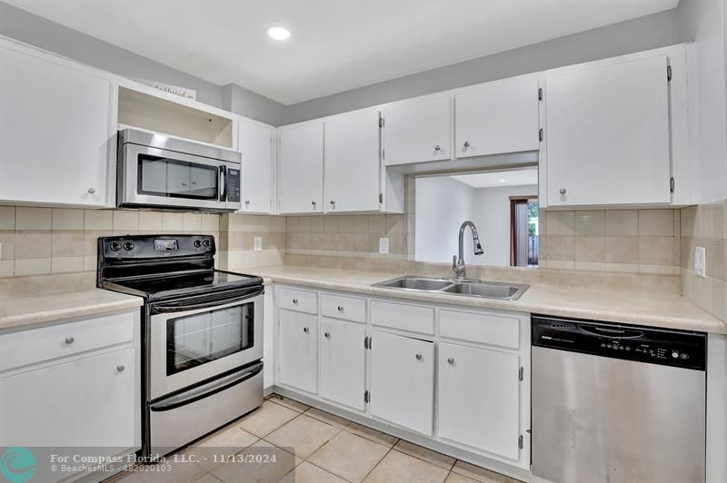 a kitchen with granite countertop a sink stove and white cabinets