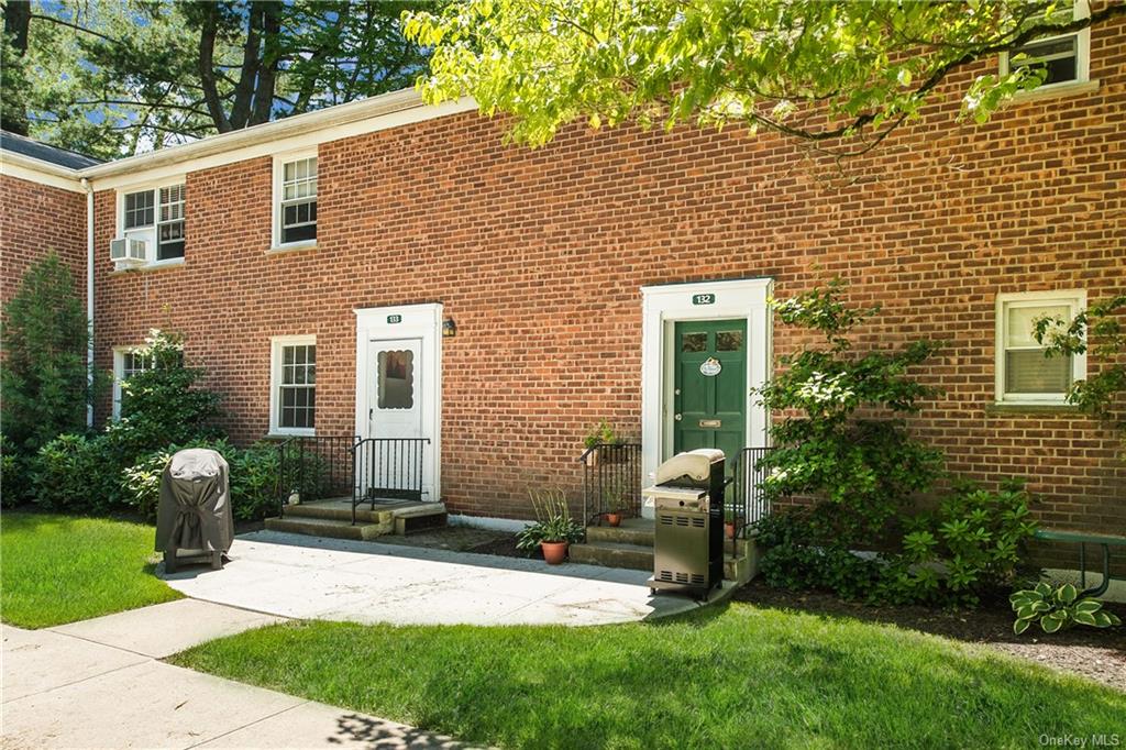 a view of a brick house with a yard and plants