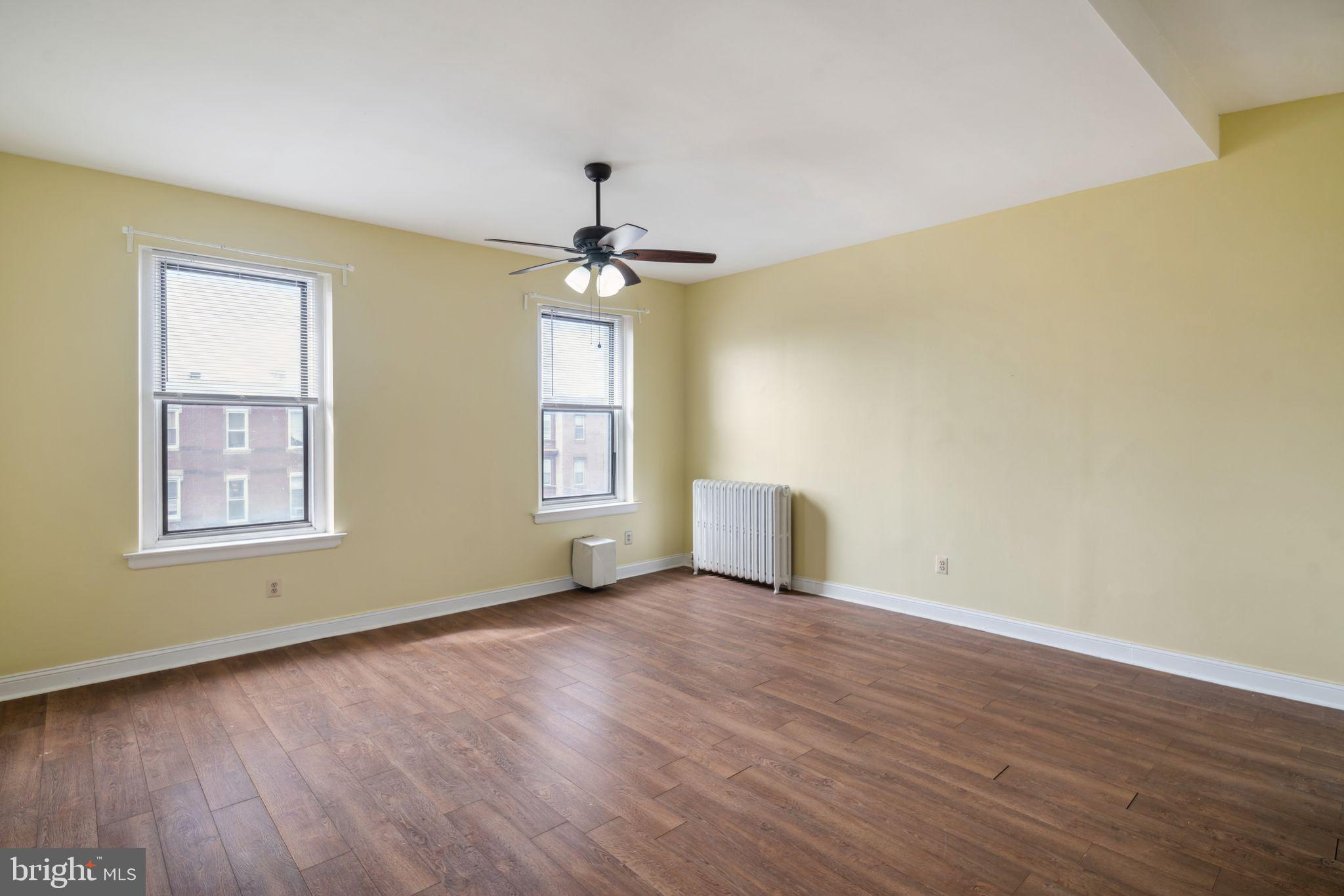 a view of an empty room with a window and wooden floor