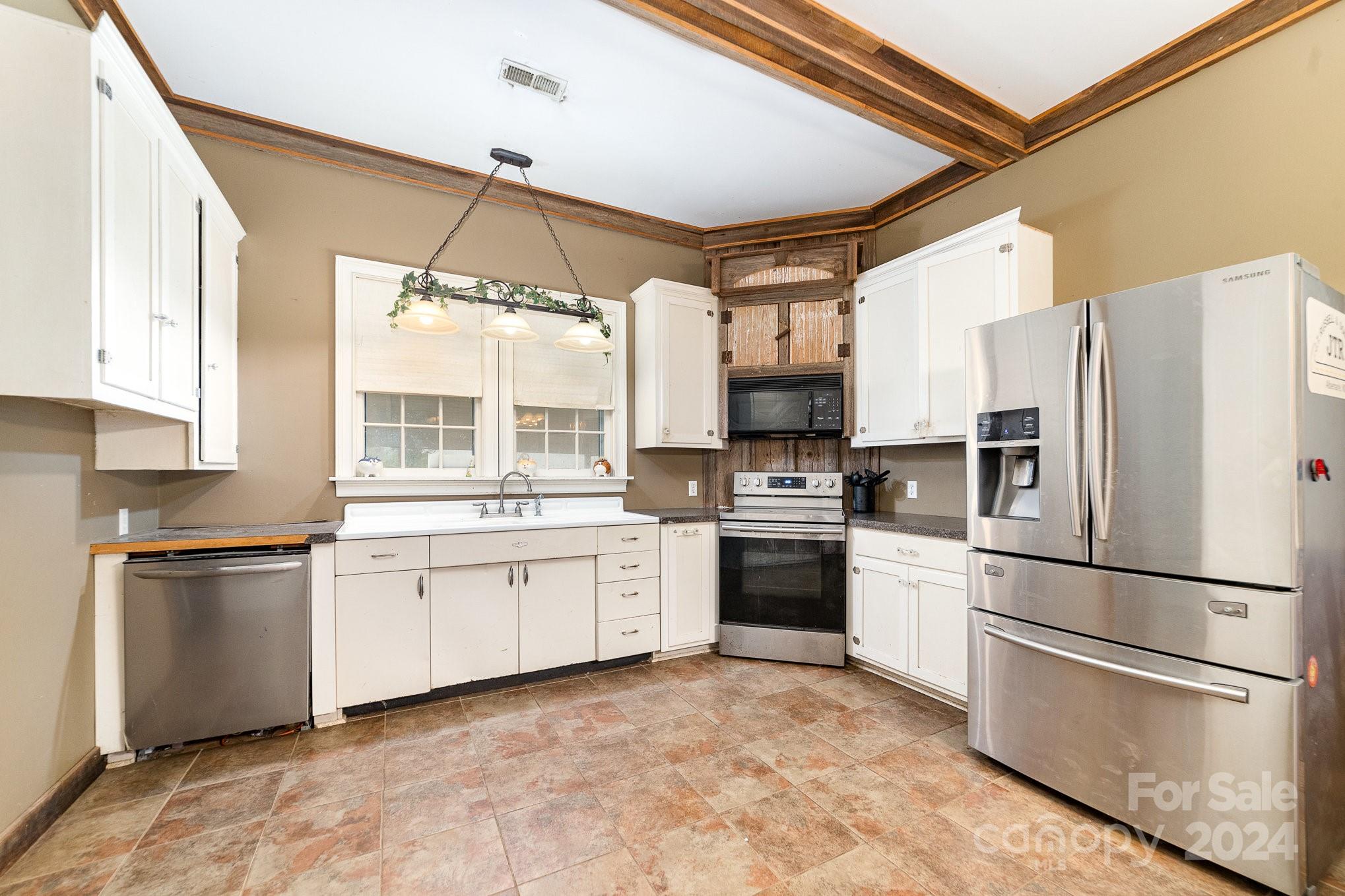 a kitchen with granite countertop a refrigerator stove top oven and sink