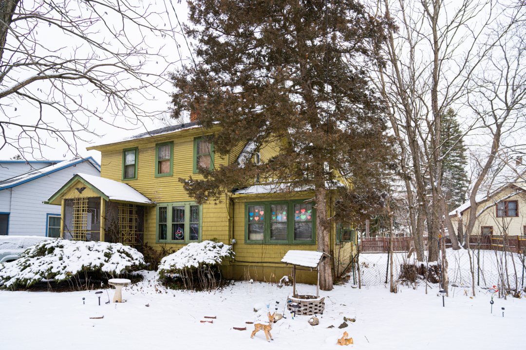 a front view of a house with a yard covered in snow