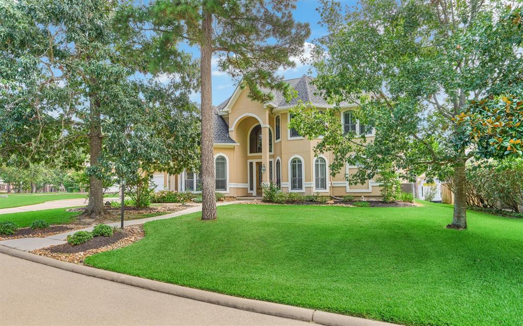 a view of a white house with a big yard and large trees