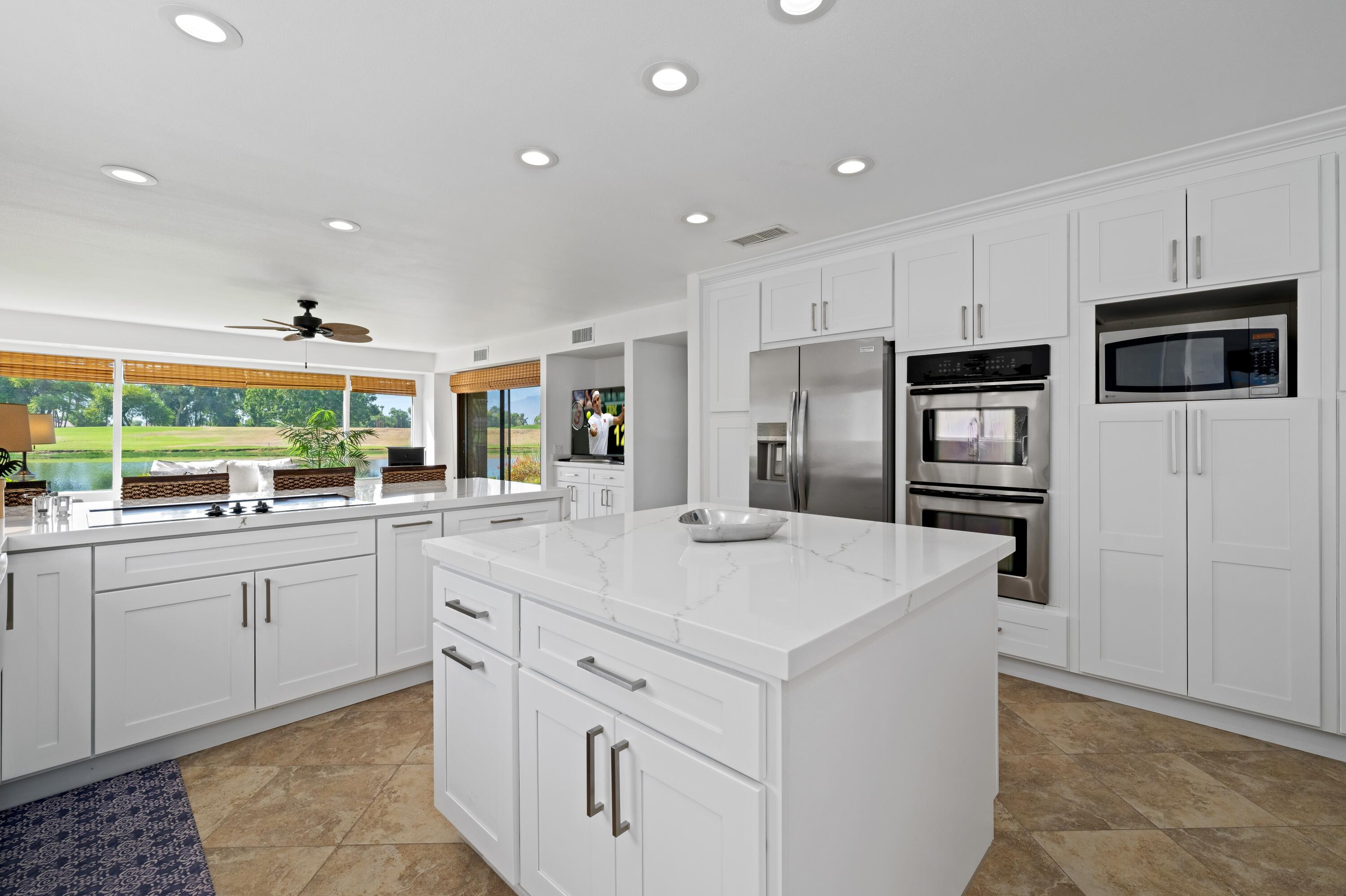 a kitchen with stainless steel appliances kitchen island granite countertop a refrigerator and a sink