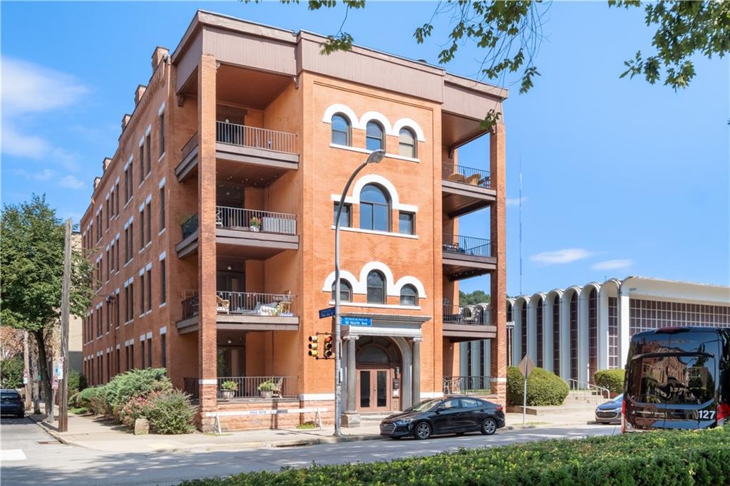 a front view of multi story residential apartment building with yard and car parked