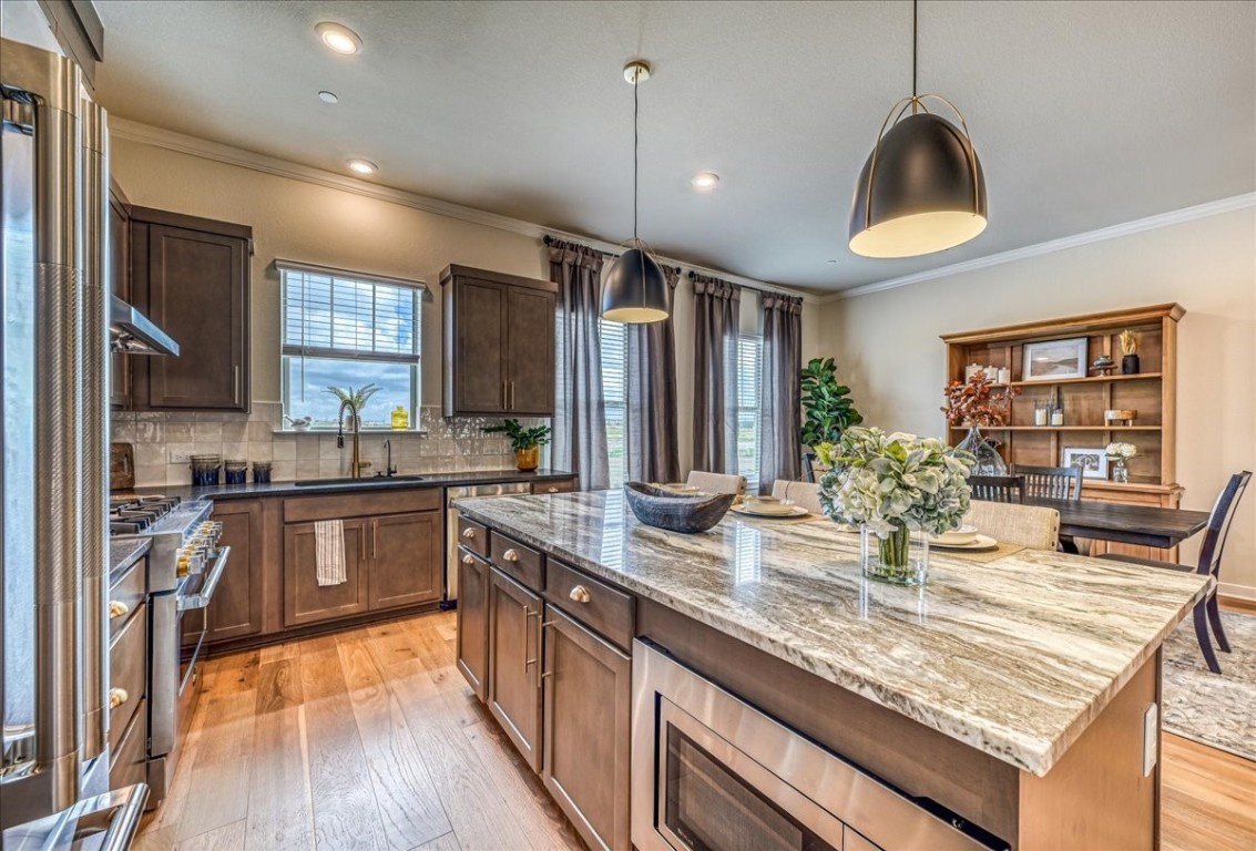 a kitchen with granite countertop a stove a sink a oven and wooden cabinets