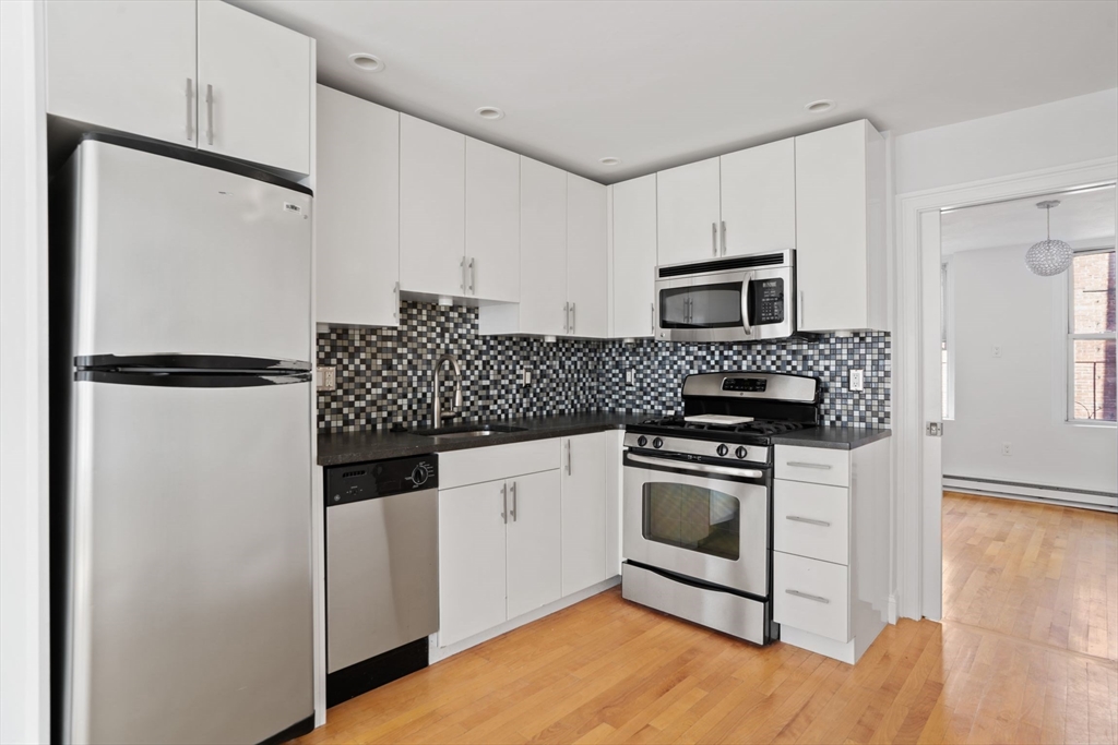 a kitchen with granite countertop a refrigerator stove and microwave