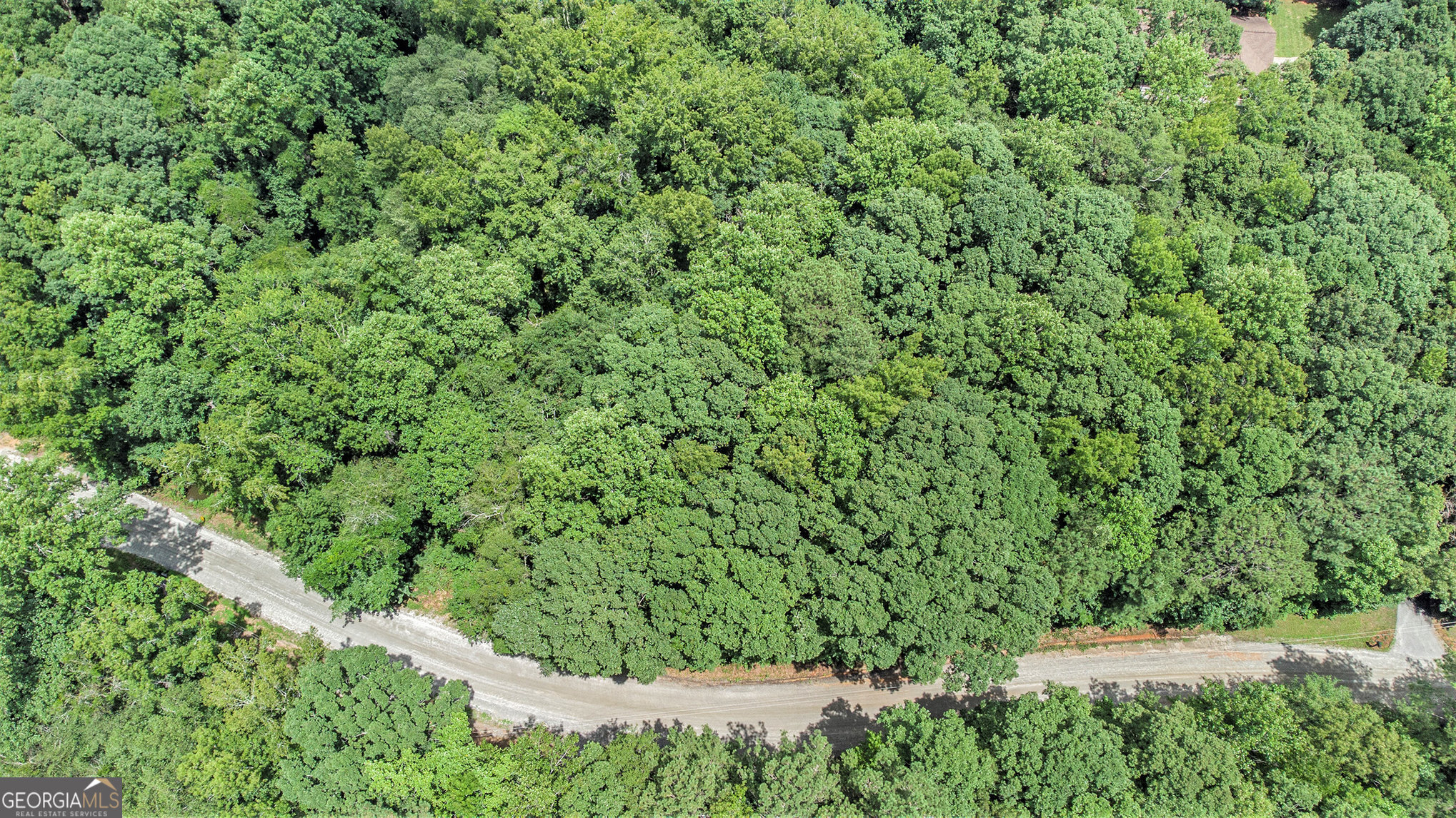 an aerial view of residential house with outdoor space and trees all around