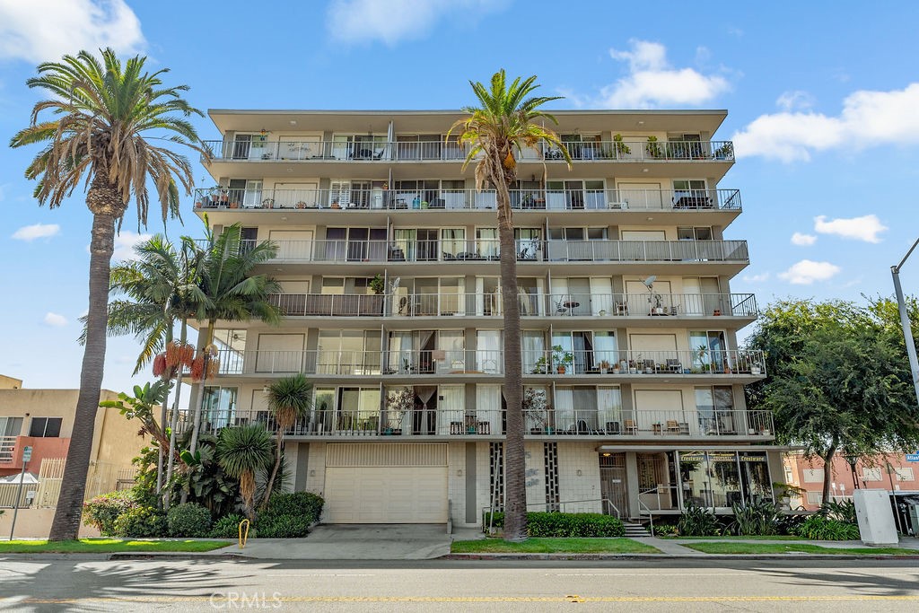 a front view of multi story residential apartment building with yard and parking space