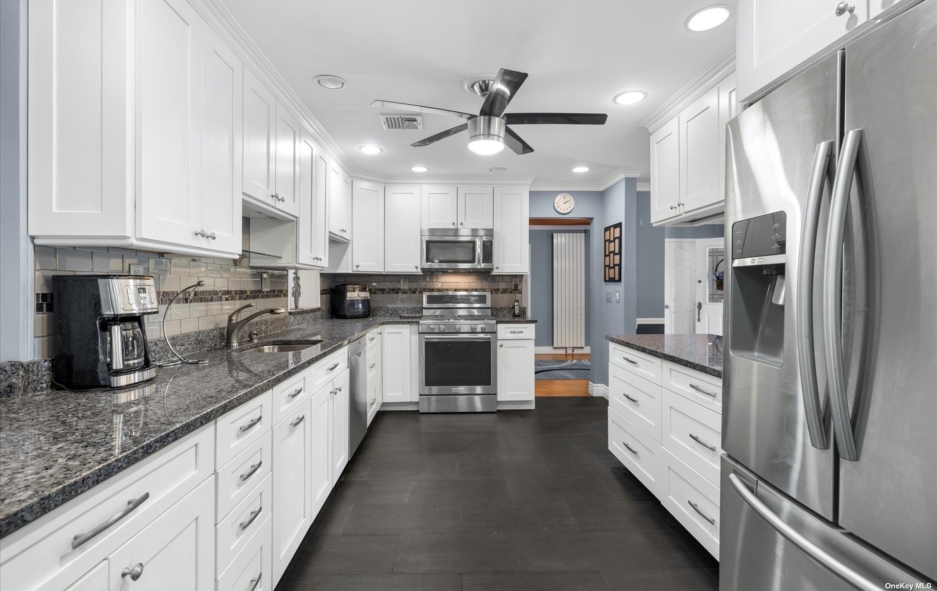 a large kitchen with stainless steel appliances granite countertop a stove refrigerator and cabinets