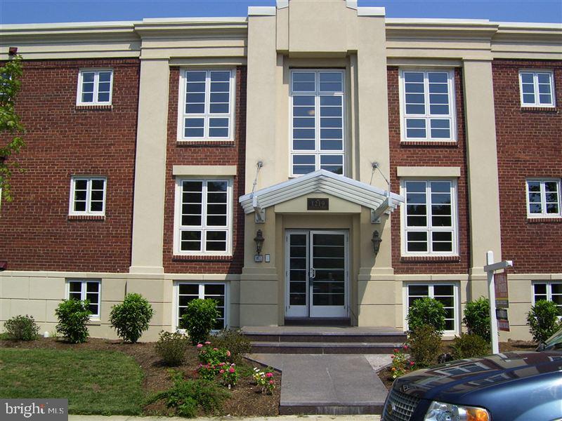 front view of a brick house with a yard and potted plants