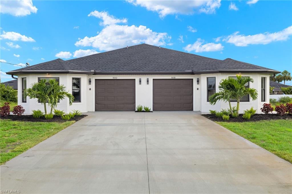 View of front of Duplex, Two one-car garages, ample parking, bay windows, and premium landscaping