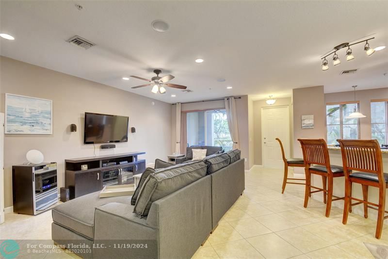 a living room with furniture kitchen view and a flat screen tv