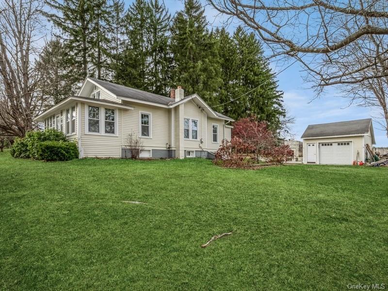 Side of home featuring a lawn, a garage.