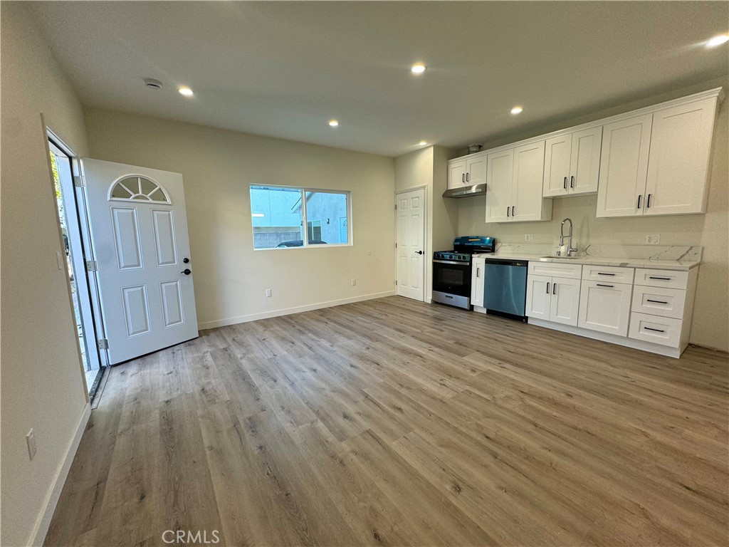 a large kitchen with stainless steel appliances granite countertop a stove and a wooden floors