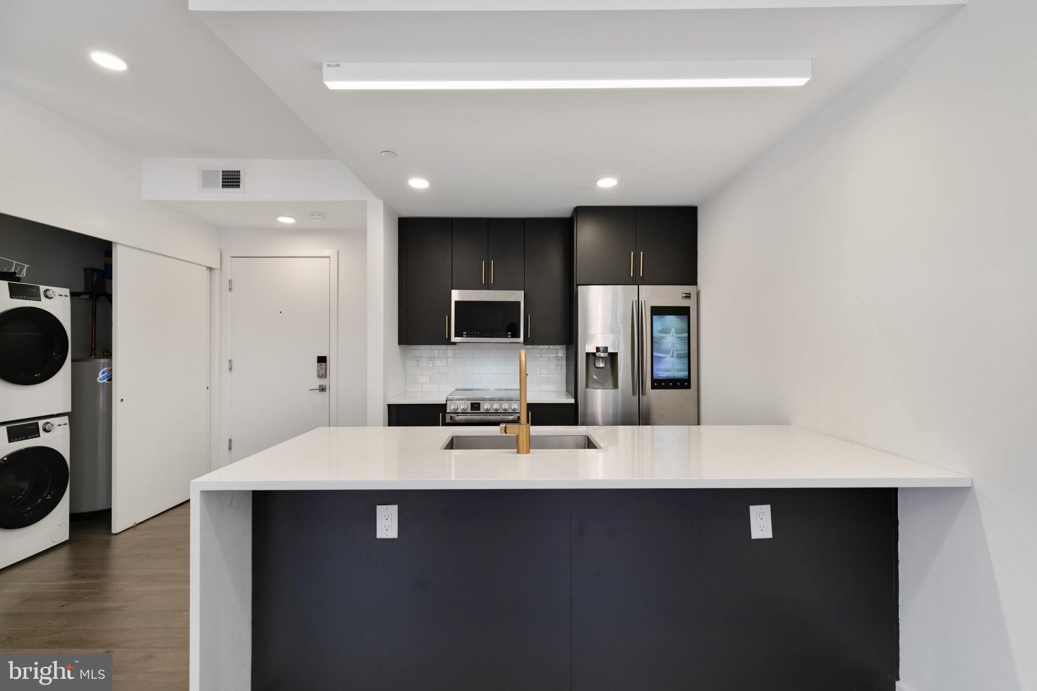 a large white kitchen with a sink stainless steel appliances and cabinets