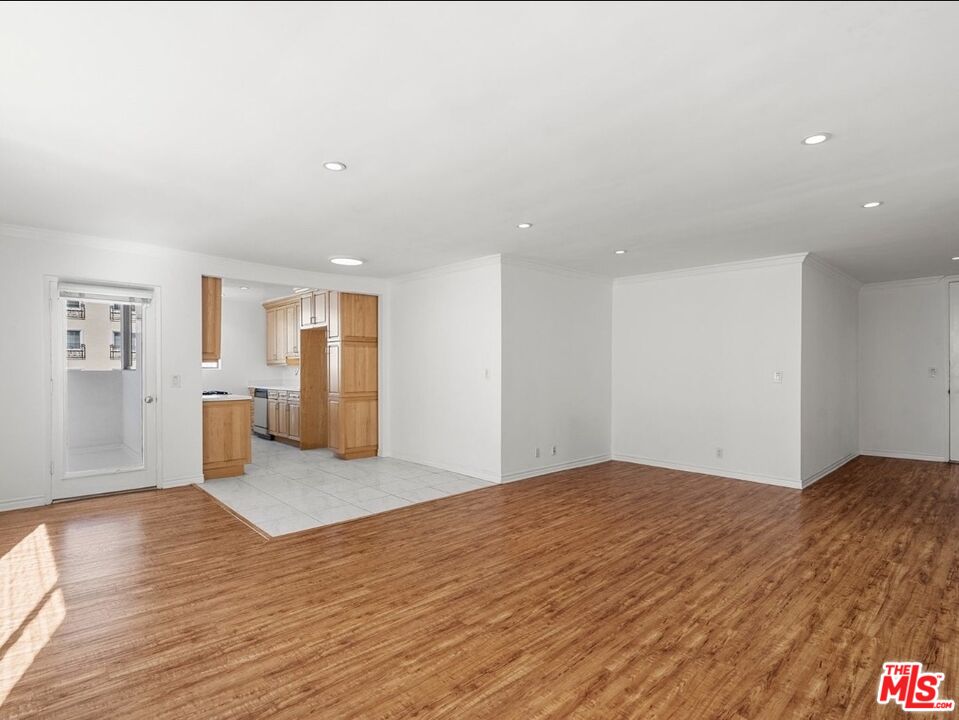 a view of a big room with wooden floor and a kitchen