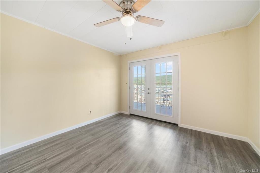 an empty room with wooden floor chandelier fan and windows