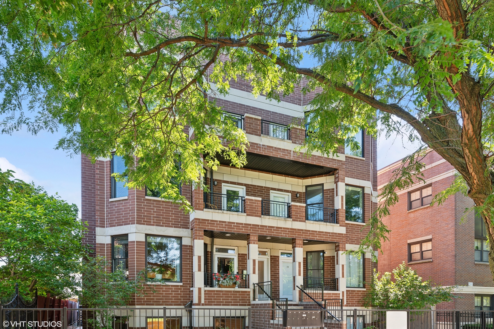 a front view of a residential apartment building with a tree