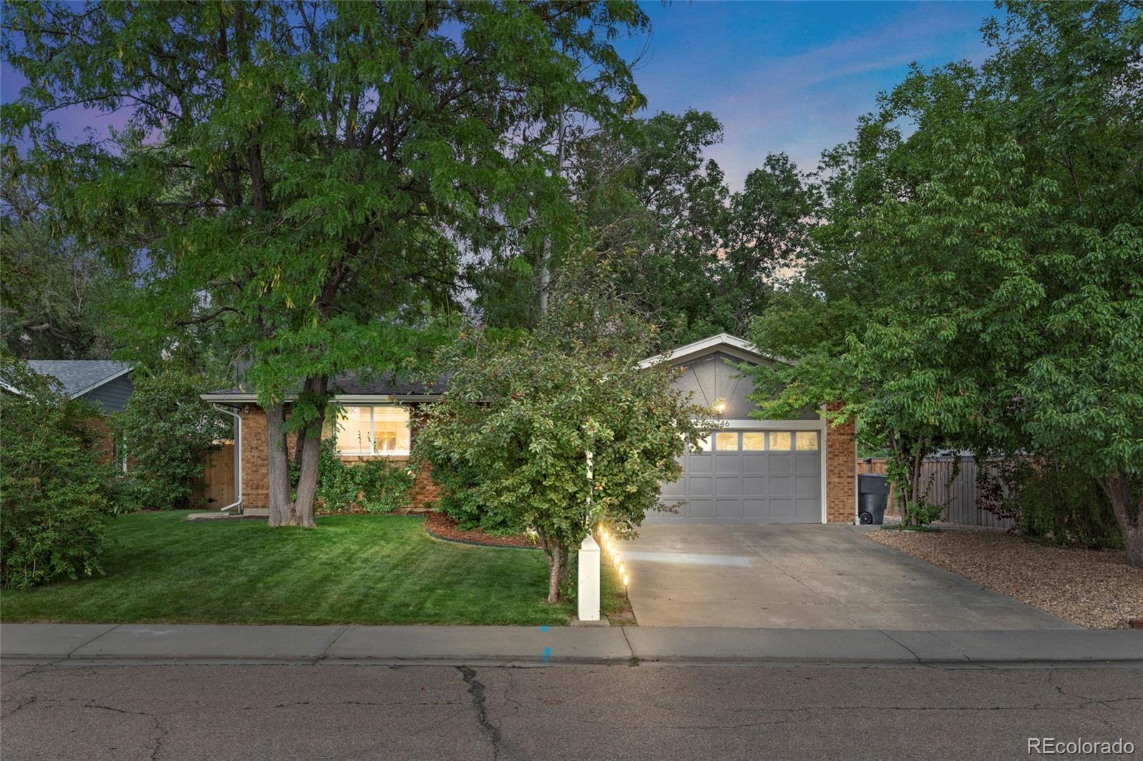 a front view of a house with a yard and tree s