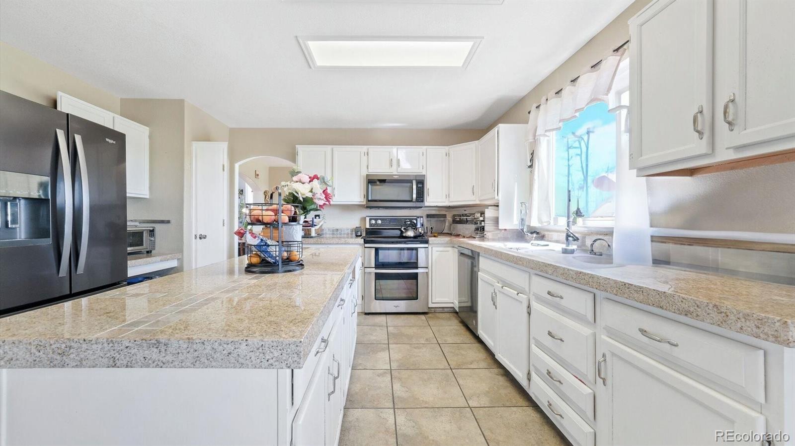 a large kitchen with granite countertop a sink counter top space appliances and cabinets