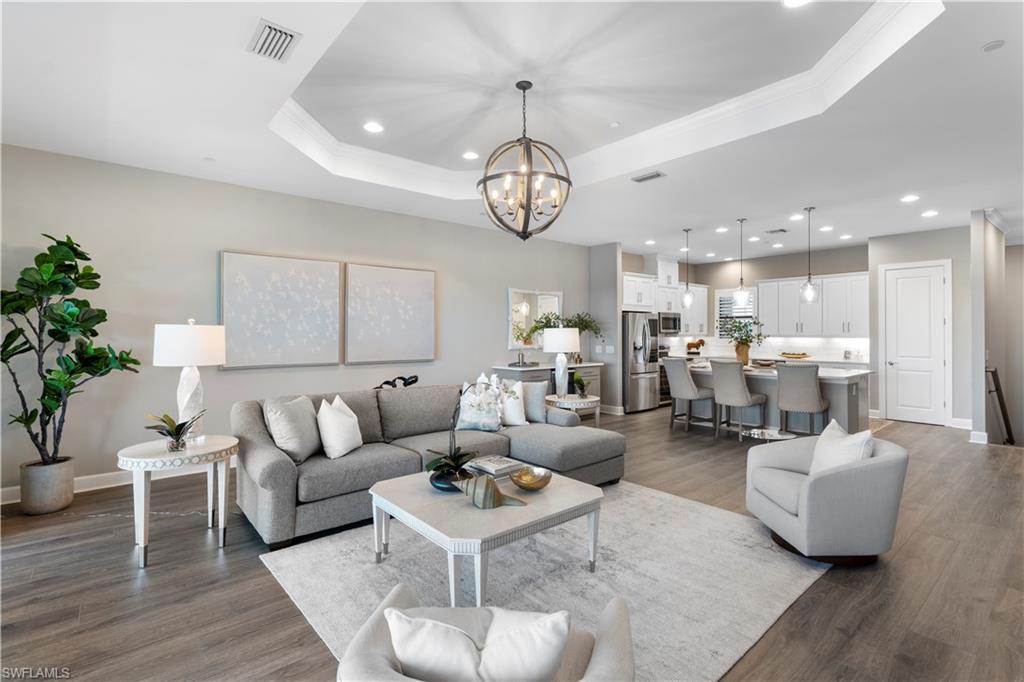 a living room with furniture kitchen view and a chandelier