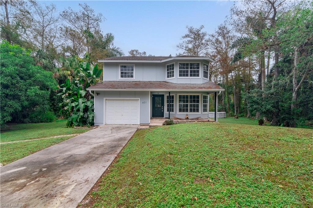 View of front property with a garage, a front lawn, and a porch