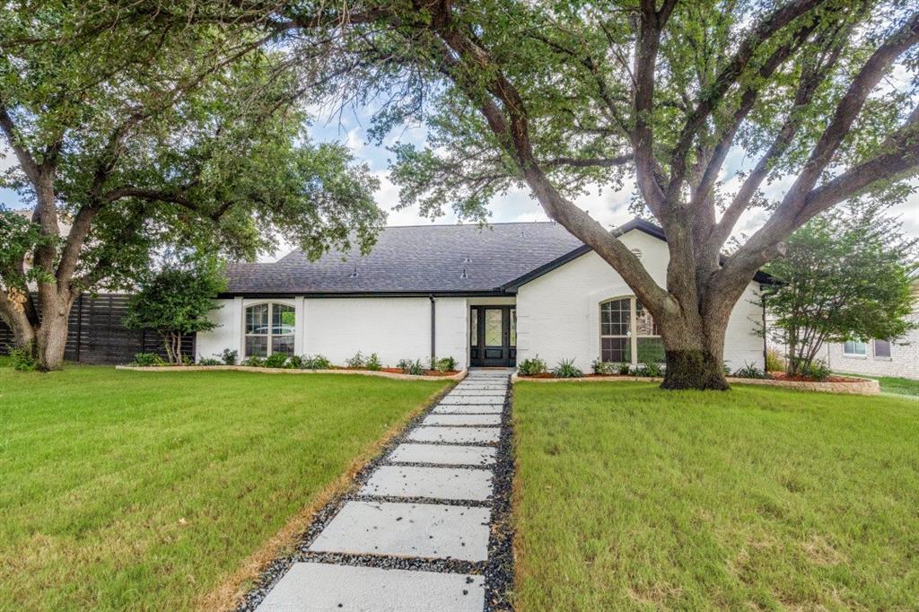 a front view of a house with a yard and trees