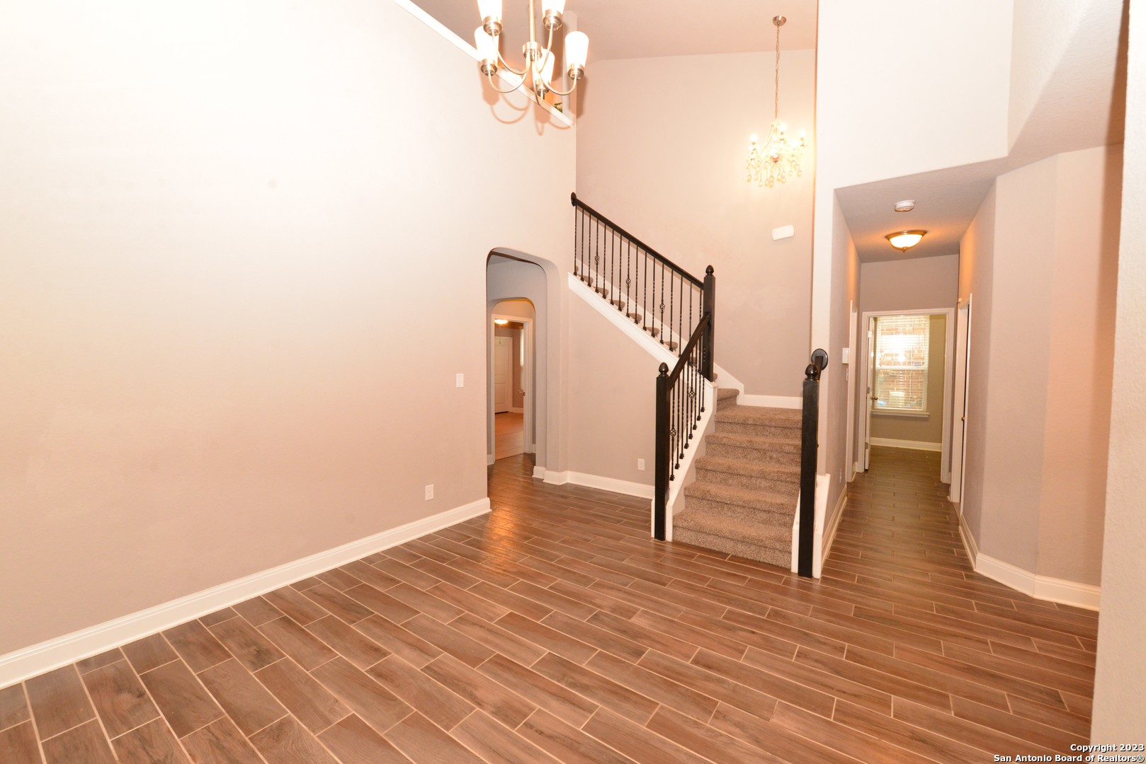 a view of an empty room with wooden floor and stairs