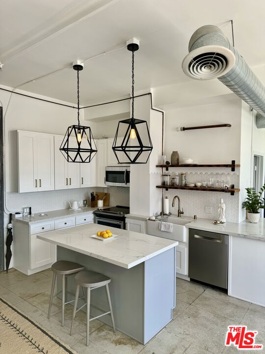 a kitchen with stainless steel appliances granite countertop a sink a stove and white cabinets