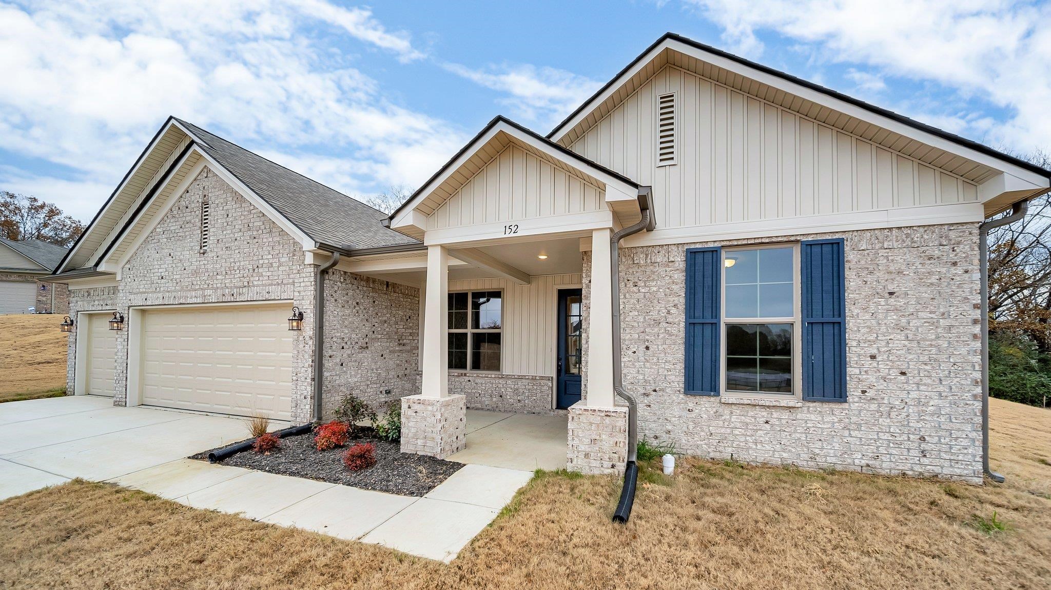 View of front of home with covered porch, a front yard, and a garage