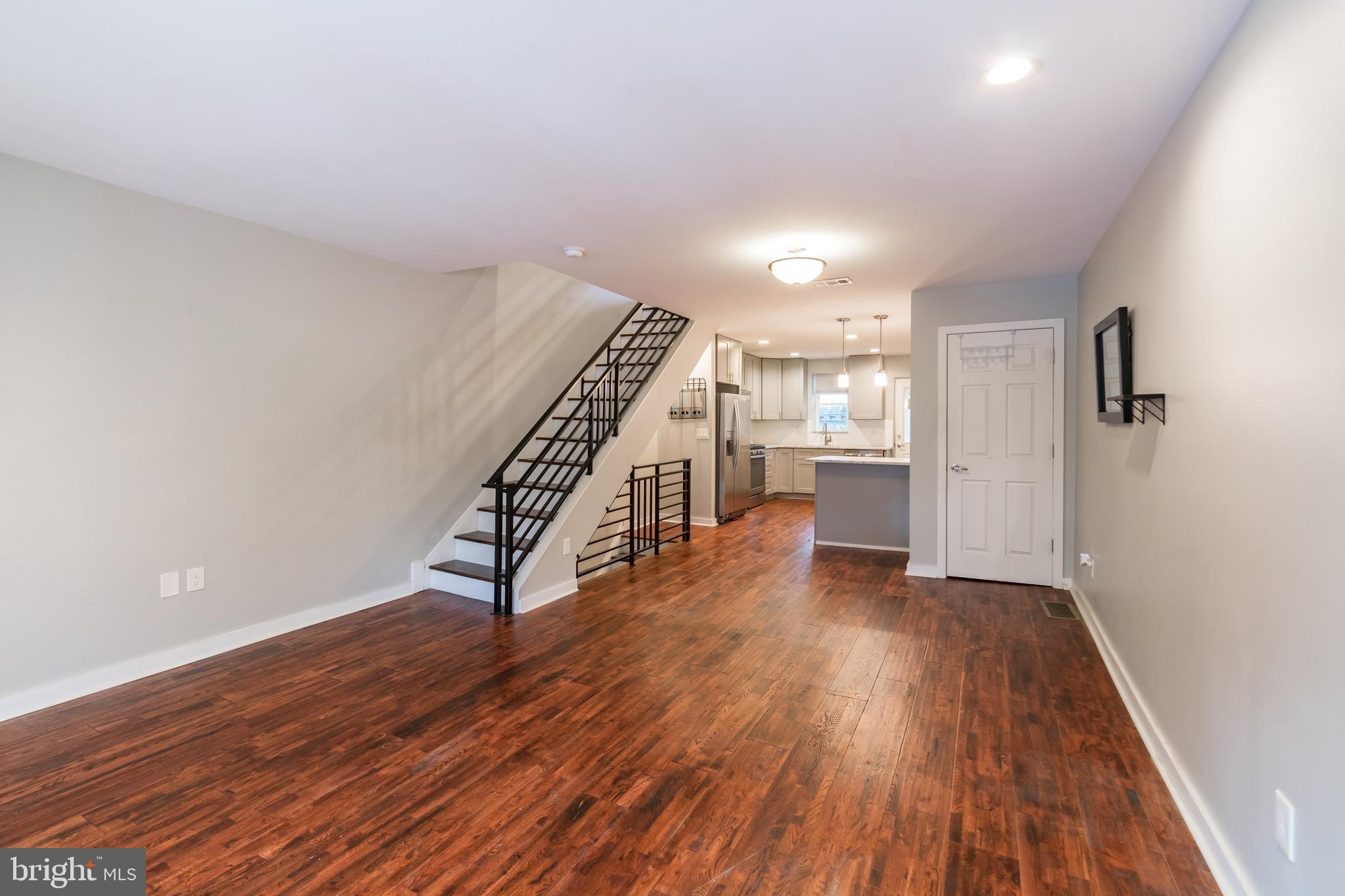 a view of an empty room with wooden floor and stairs