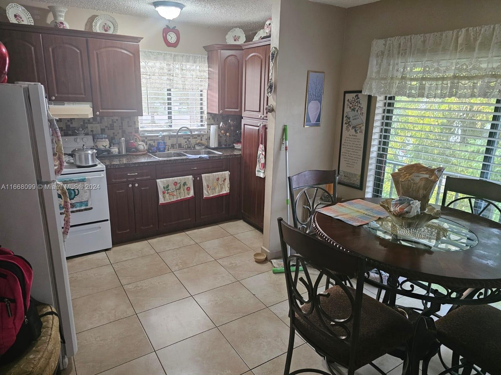 a kitchen with stainless steel appliances granite countertop a sink a stove a refrigerator a dining table and chairs