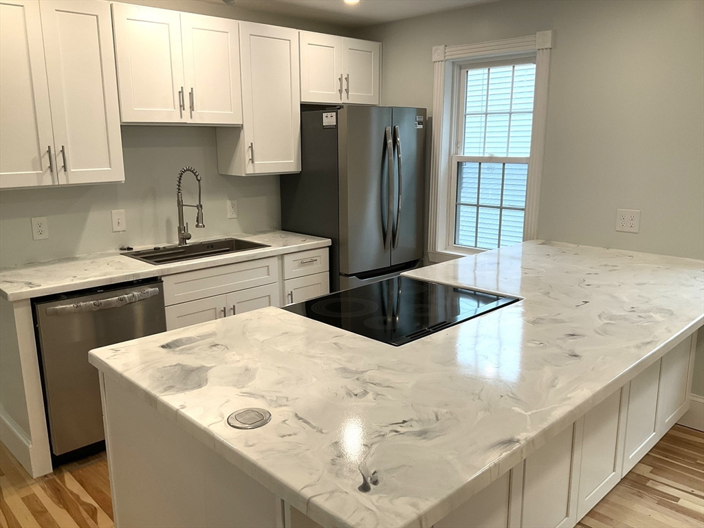 a kitchen with stainless steel appliances kitchen island a white counter space and a window