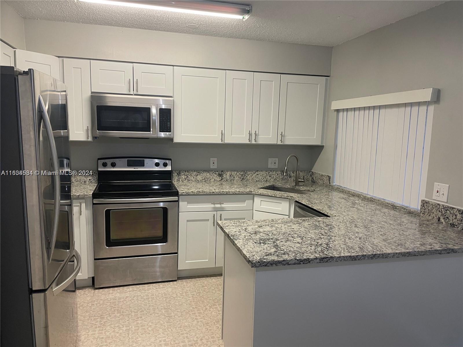 a kitchen with granite countertop a sink stove and refrigerator