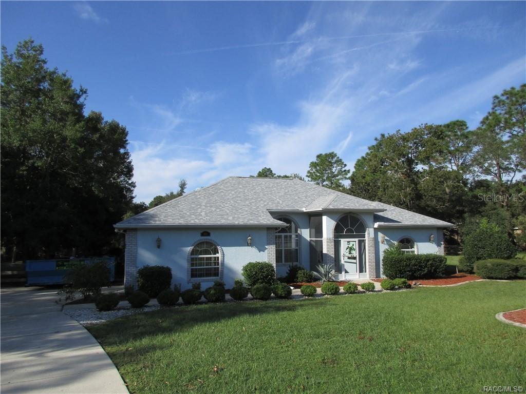 a front view of a house with a garden and trees