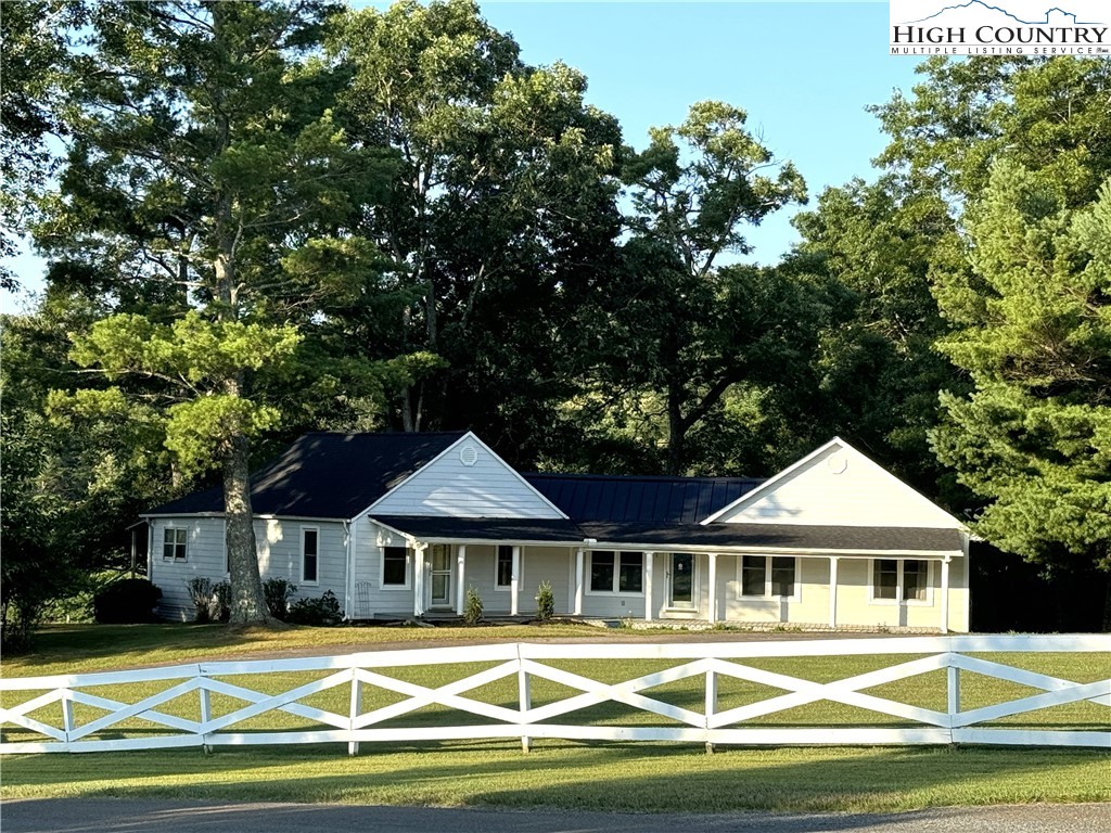 a view of a white house with a swimming pool and lawn chairs under an umbrella