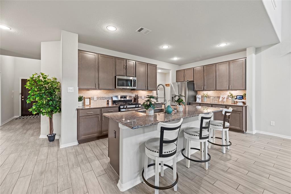 Kitchen features granite counters and stainless appliances including the refrigerator.