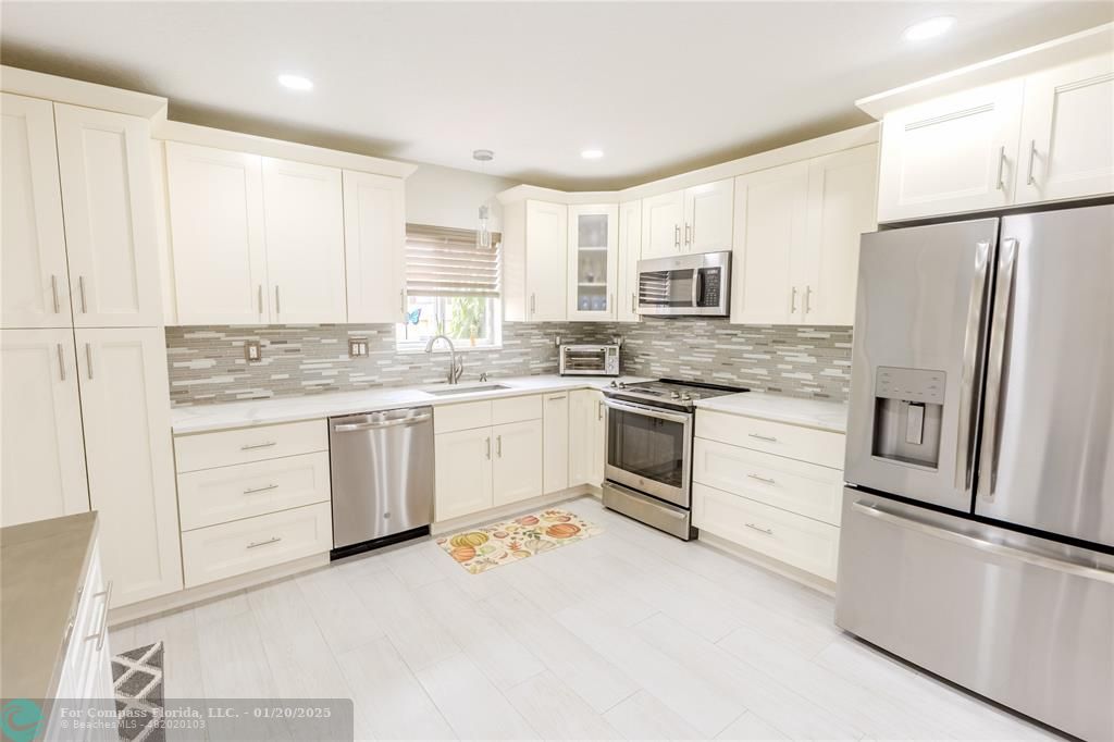 a kitchen with white cabinets stainless steel appliances and a sink