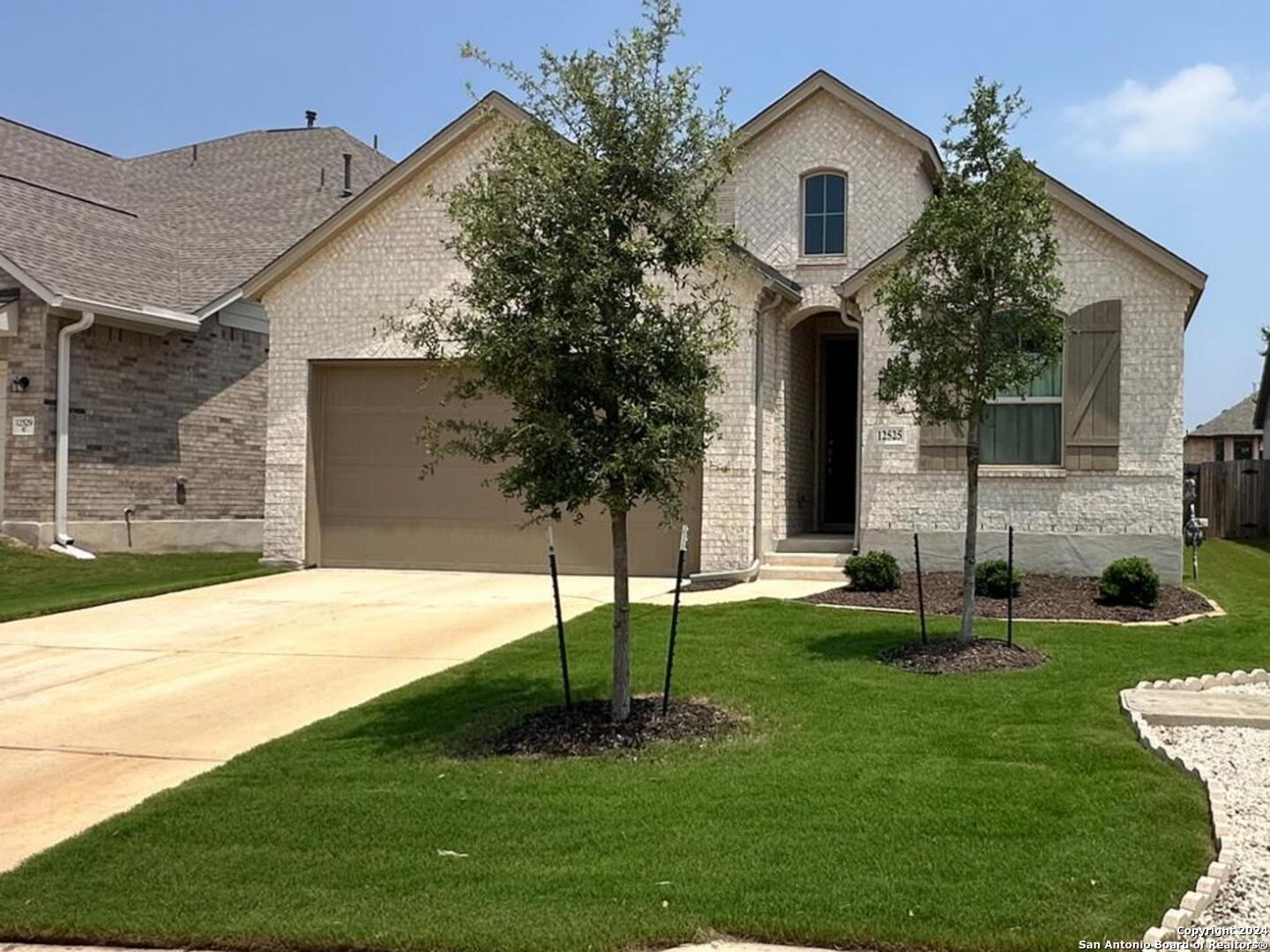 a front view of a house with garden and trees