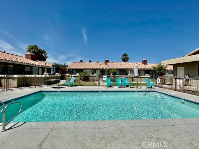 a view of a swimming pool with lawn chairs and a big yard