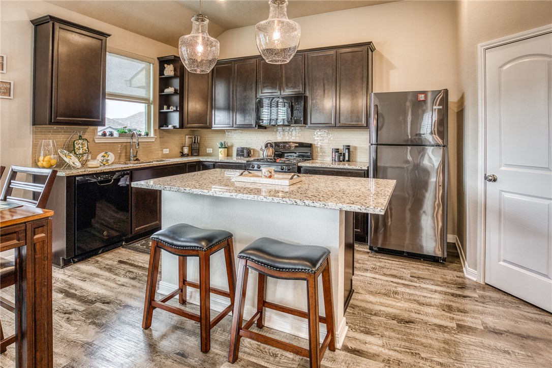 Kitchen with dark brown cabinetry, hanging light f