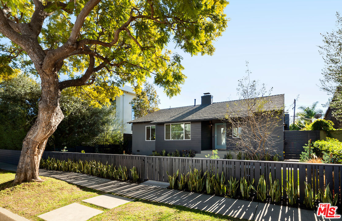 a view of a house with a small yard plants and wooden fence