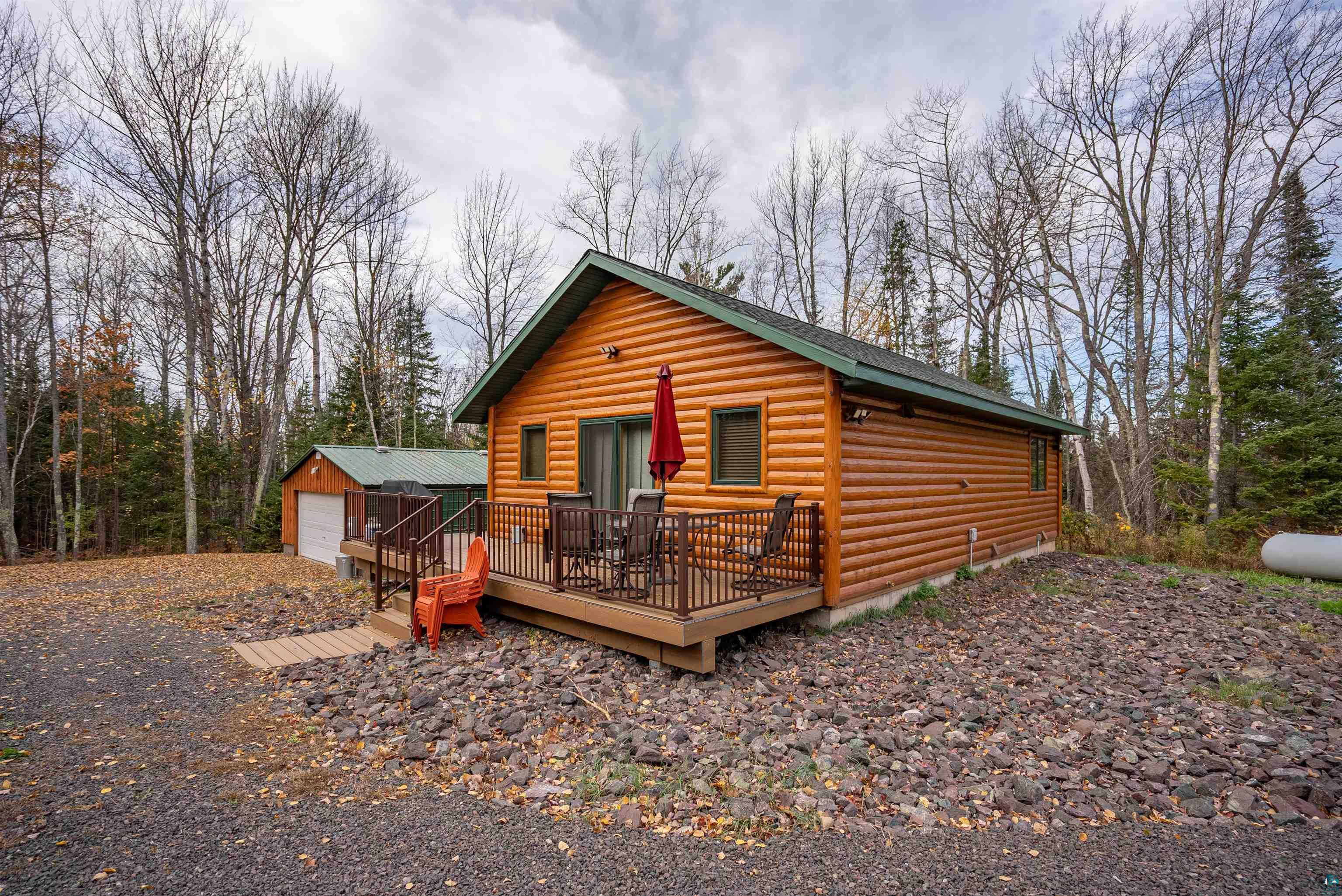 Log-style house featuring a deck, an outbuilding, and a garage