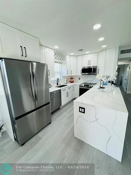 a kitchen with stainless steel appliances a refrigerator sink a stove a microwave a sink and cabinets