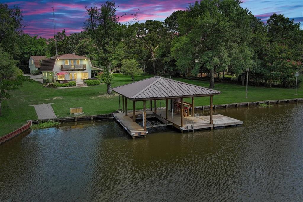 an aerial view of a house with swimming pool a yard and lake view